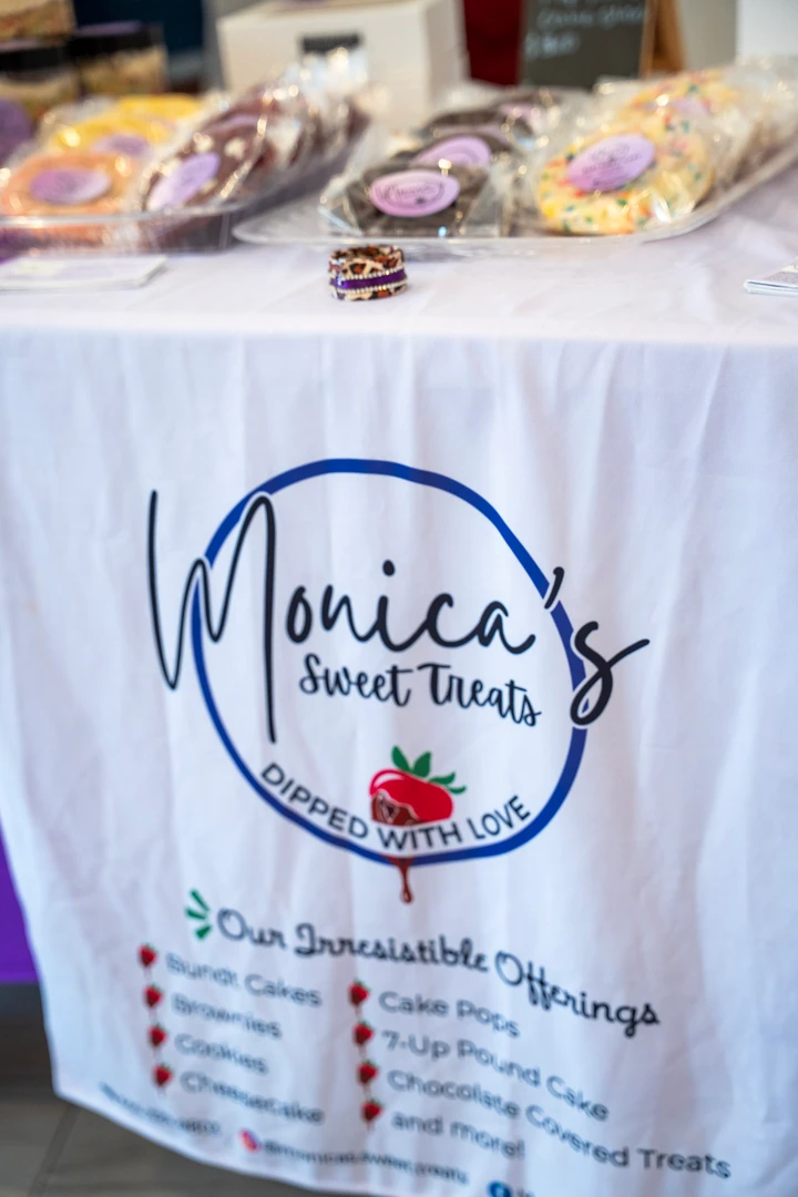 A Monica’s Cookie Crumbs banner beneath a baked-goods table.