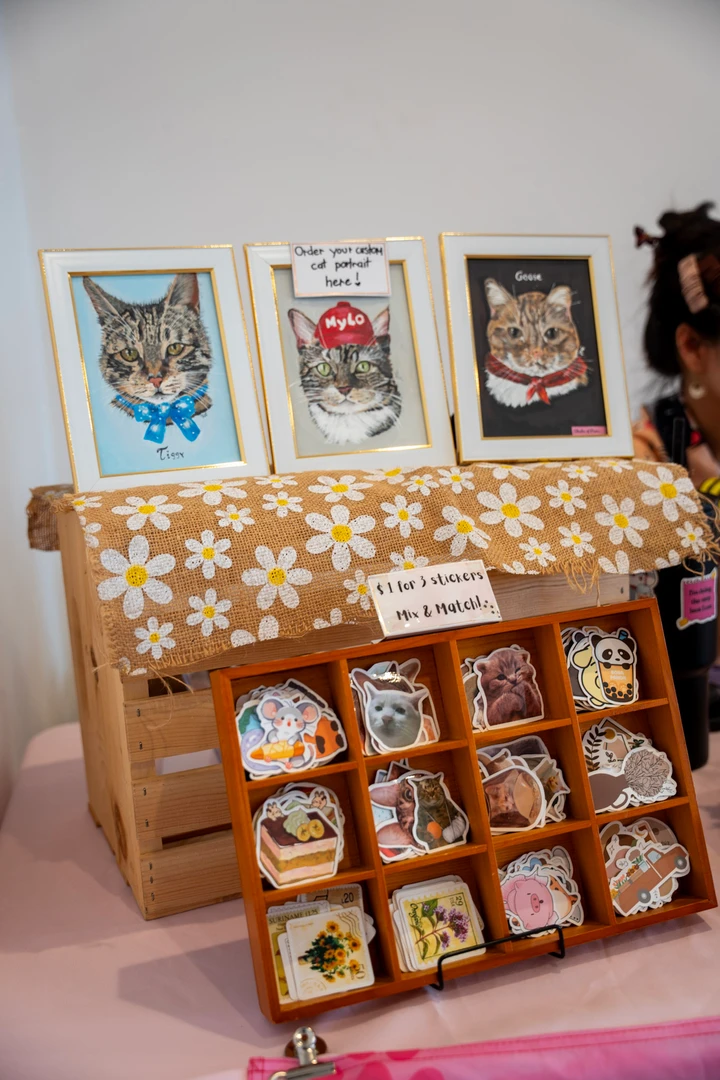 Cat-themed prints, accessories and small handmade items on a market table.