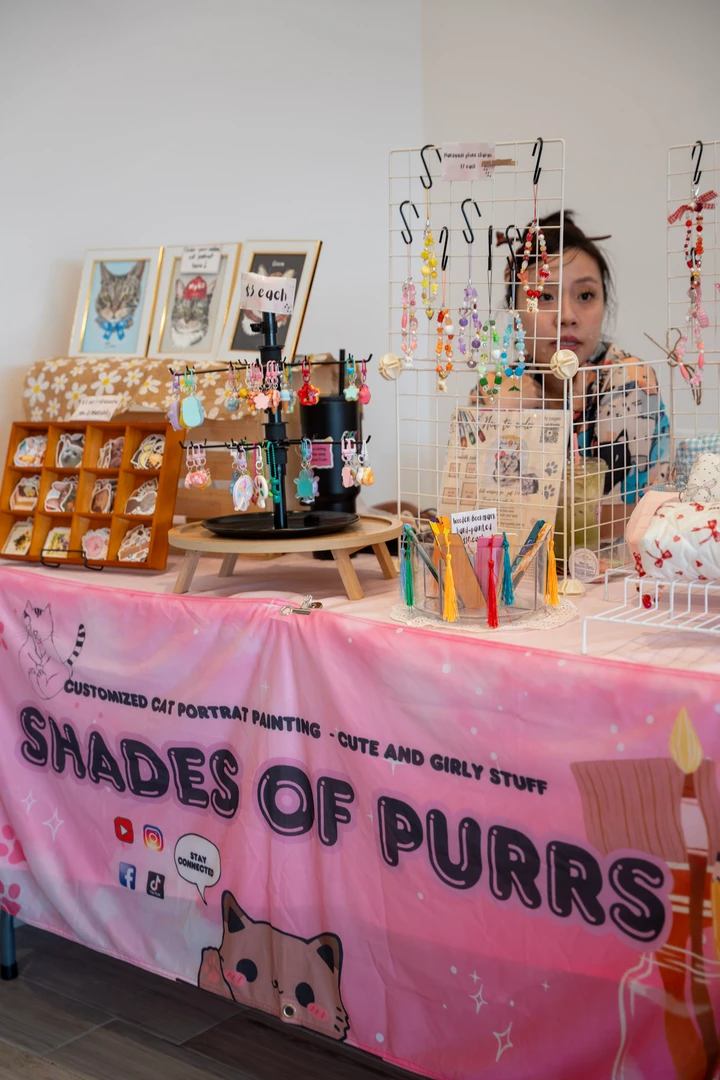 Cat-themed prints, accessories and small handmade items on a market table.