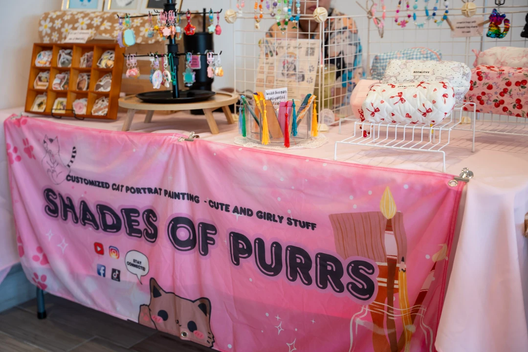 Cat-themed prints, accessories and small handmade items on a market table.