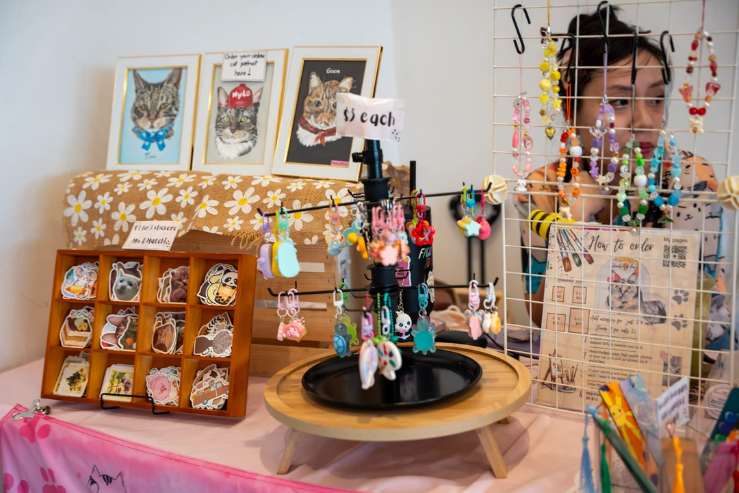 Cat-themed prints, accessories and small handmade items on a market table.