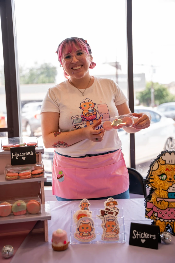 A maker in a pink apron holding a decorated treat.