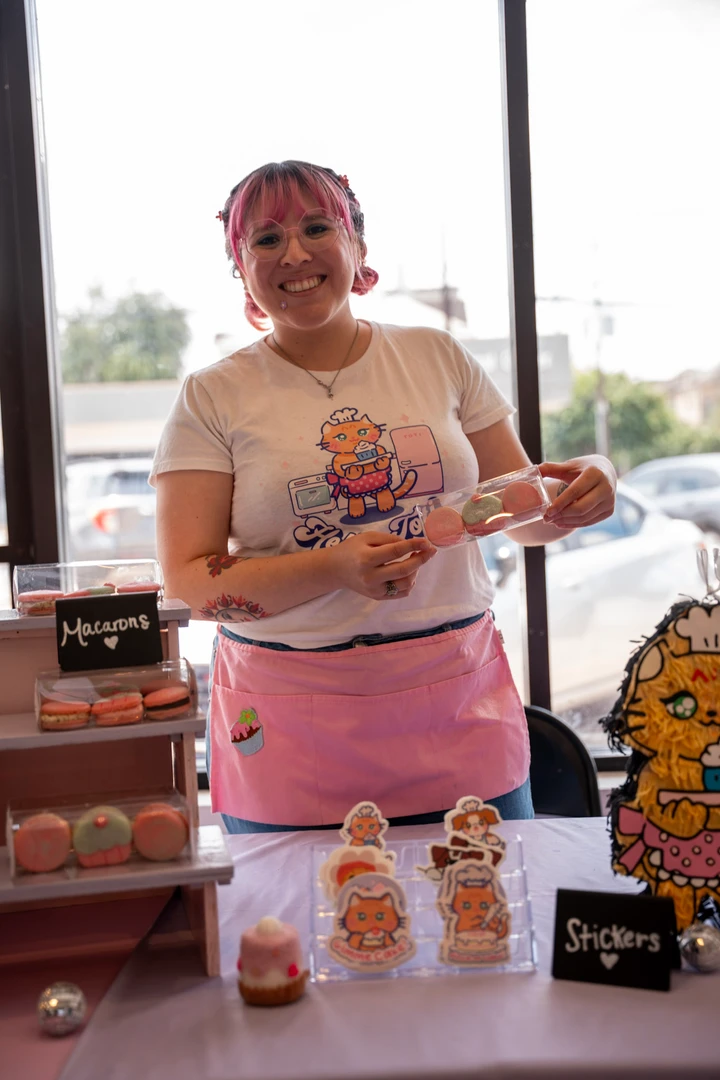 A maker in a pink apron holding a decorated treat.