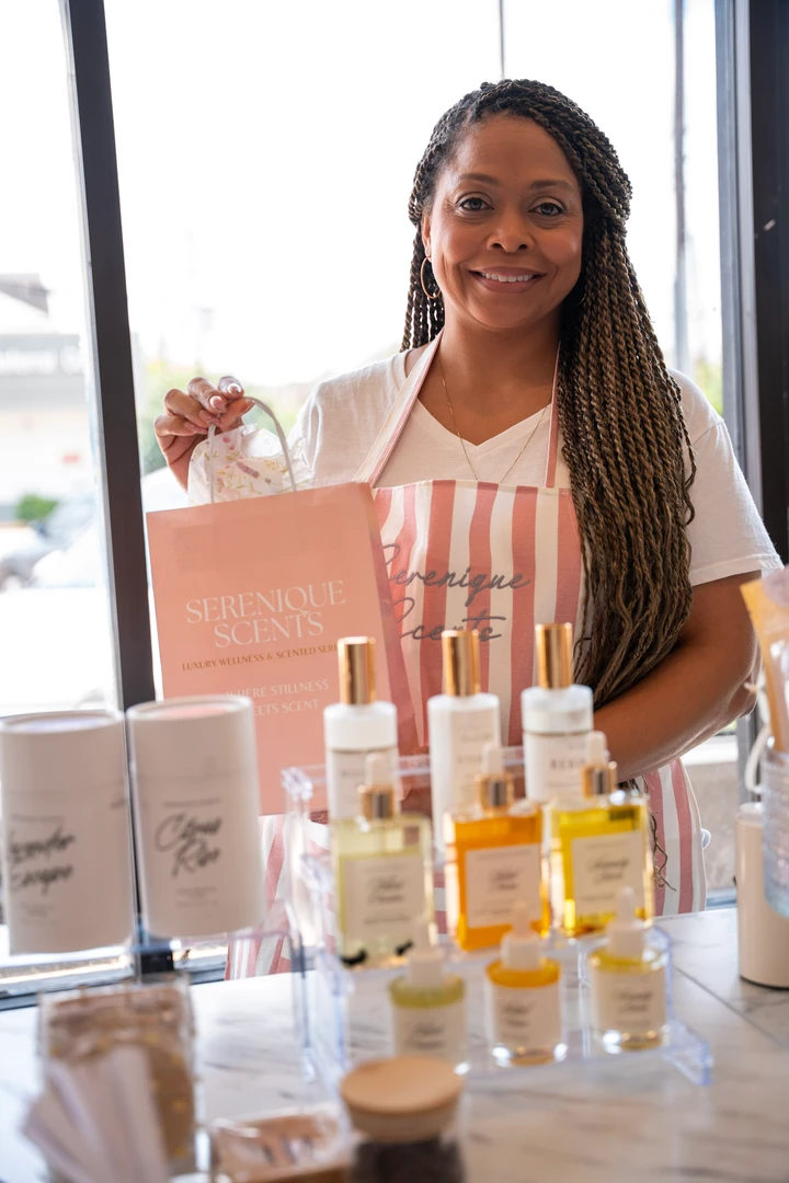 A maker standing behind a table of beauty products.
