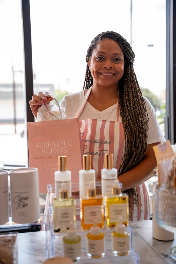 A maker standing behind a table of beauty products.