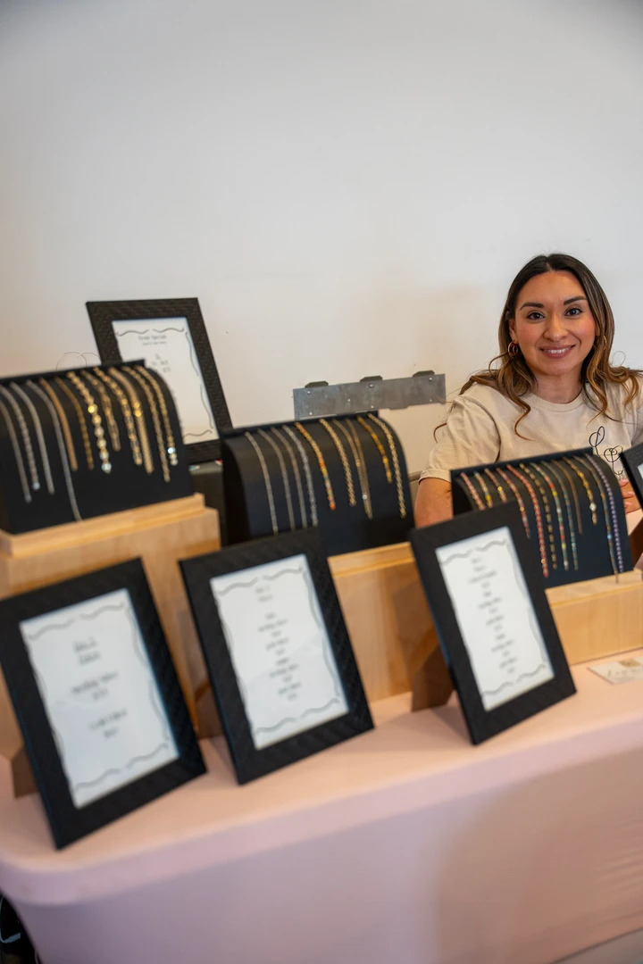 A maker behind a table of framed pieces and paper goods.