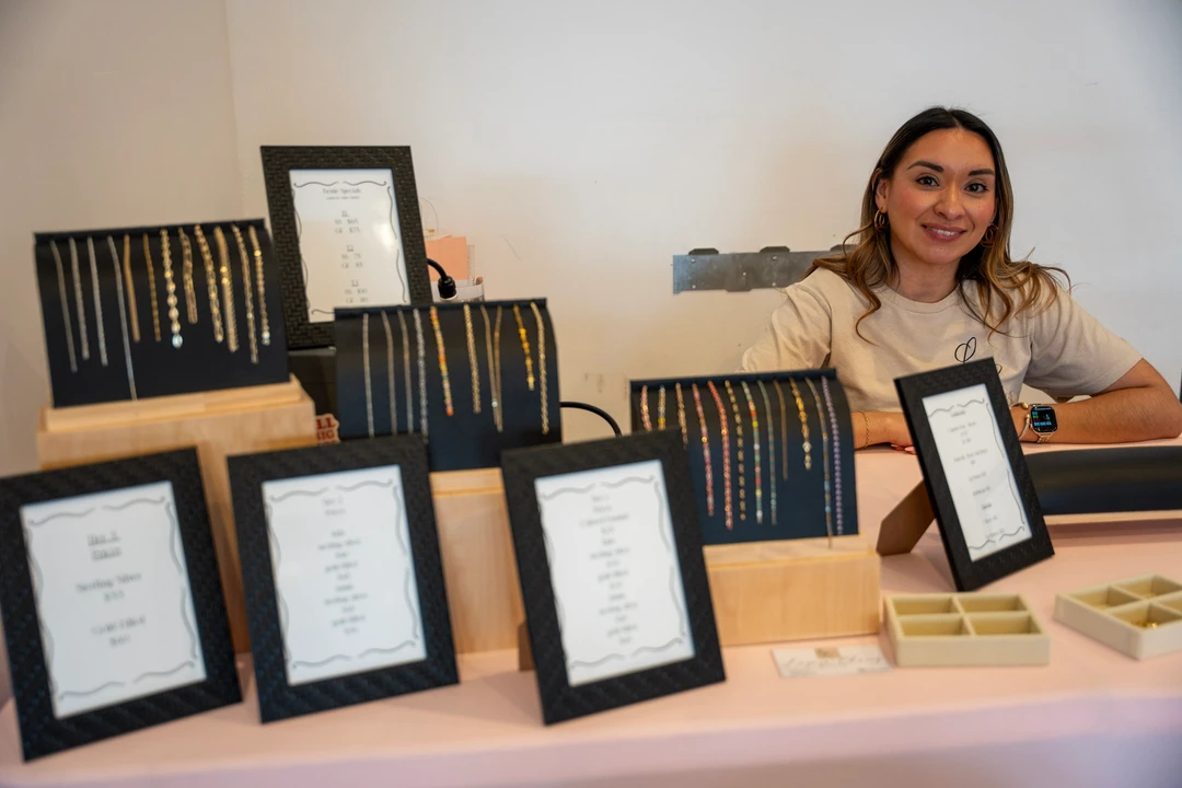 A maker behind a table of framed pieces and paper goods.