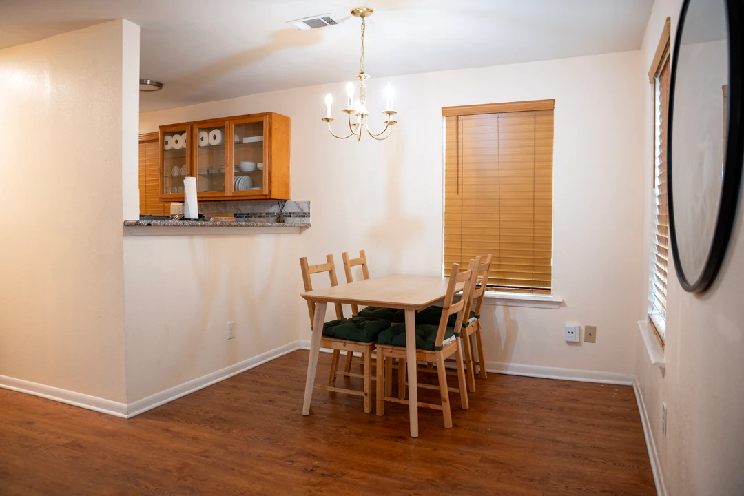 A wooden dining table beside an open kitchen and warm wood flooring.