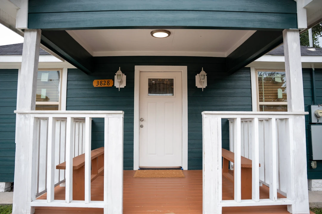 A covered front porch with teal siding and white railings.