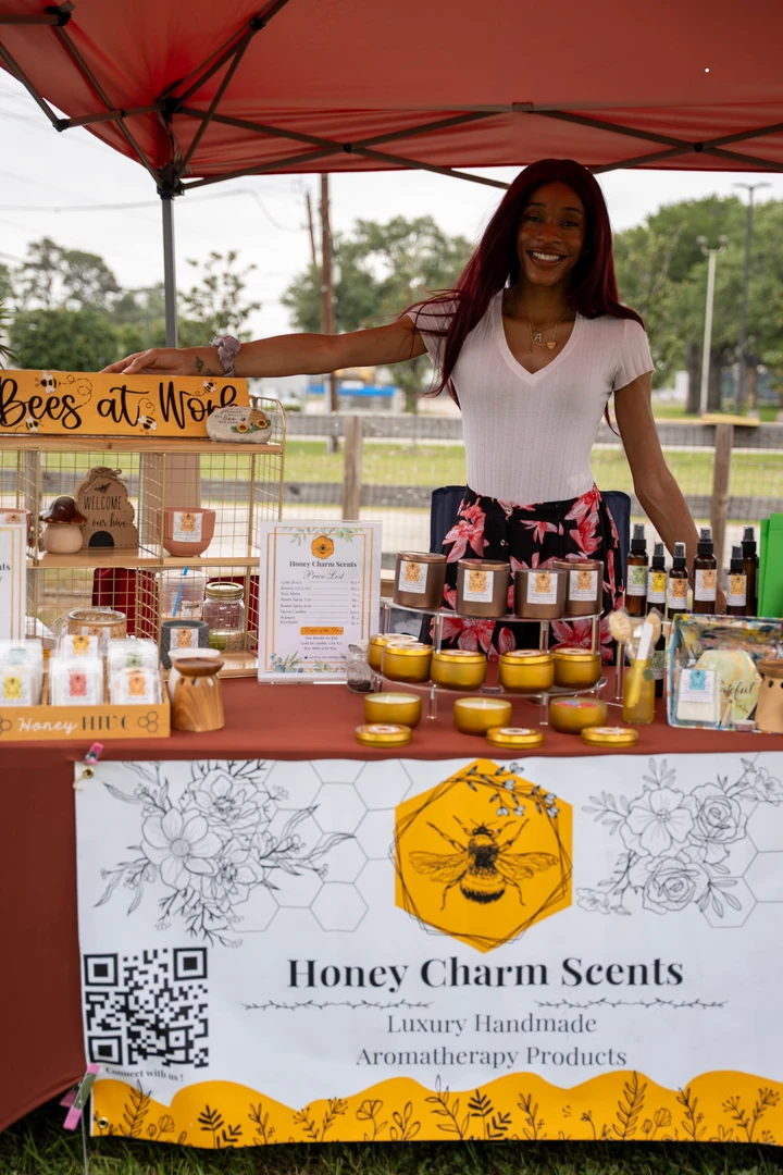 A smiling candle maker in white at the Honey Charm Scents stall.