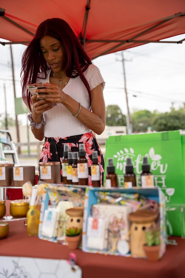 A candle maker examining a jar at her outdoor stall.