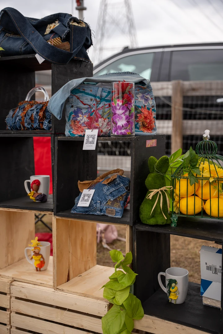 Colorful goods and plants arranged on wooden market shelves.