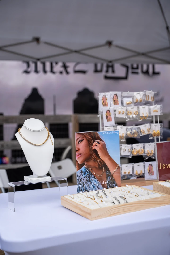 Jewelry and clothing displayed beneath a white market canopy.