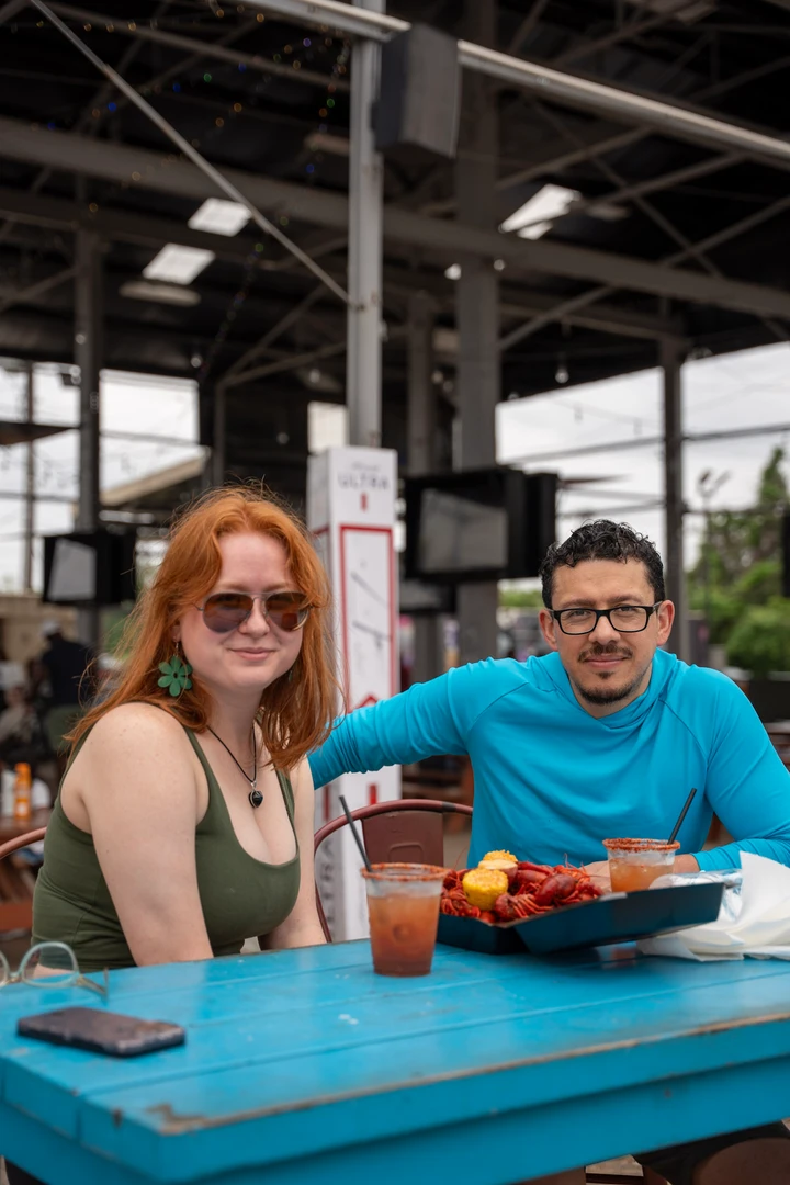 Market visitors sharing food at picnic tables.