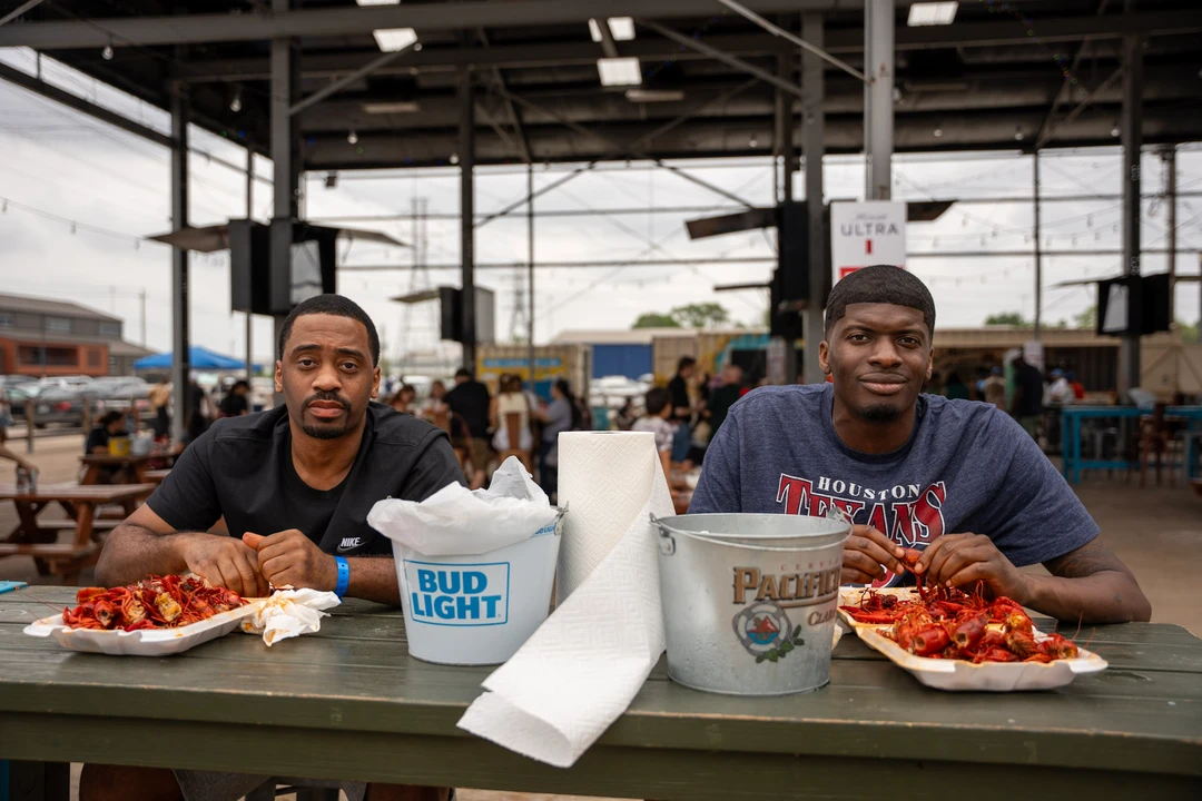 Market visitors sharing food at picnic tables.