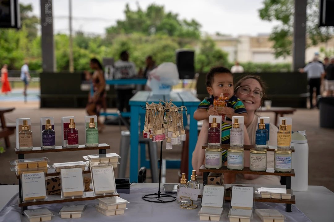 Two makers stand behind an arrangement of candles and potted plants.