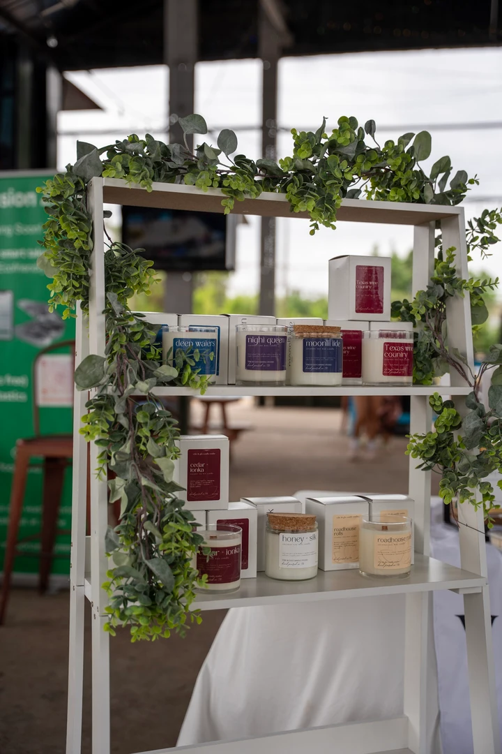 Candles and greenery arranged on a tall display shelf.