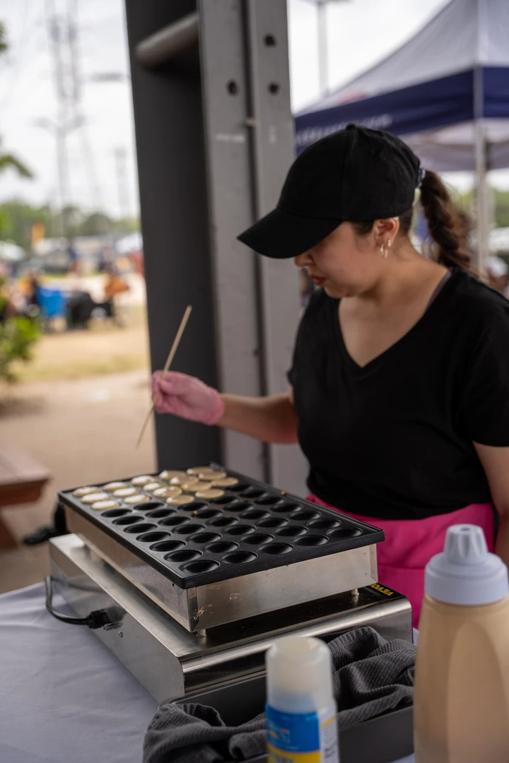 A maker working over a compartmented tray at an outdoor stall.