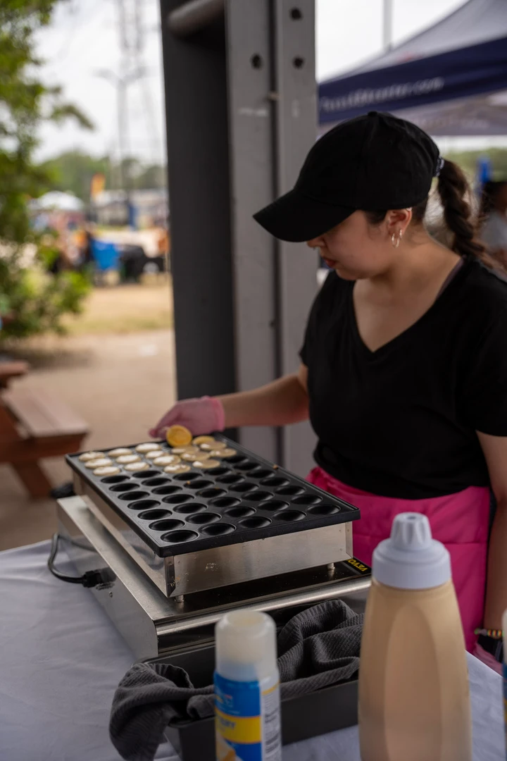 A maker working over a compartmented tray at an outdoor stall.