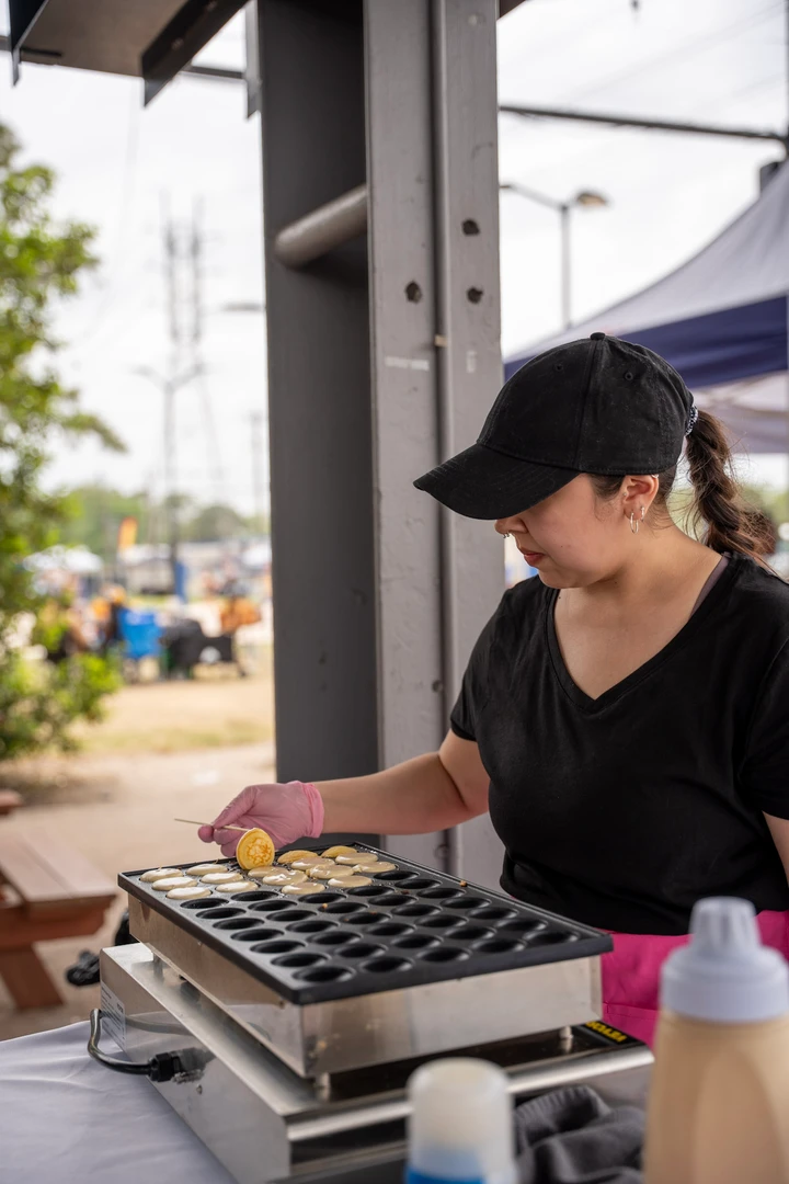 A maker working over a compartmented tray at an outdoor stall.