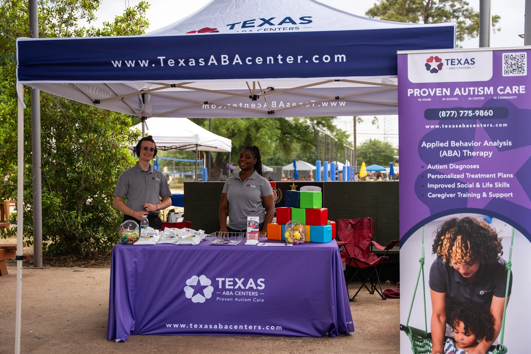 Vendors behind a purple Texas-branded table at the outdoor market.