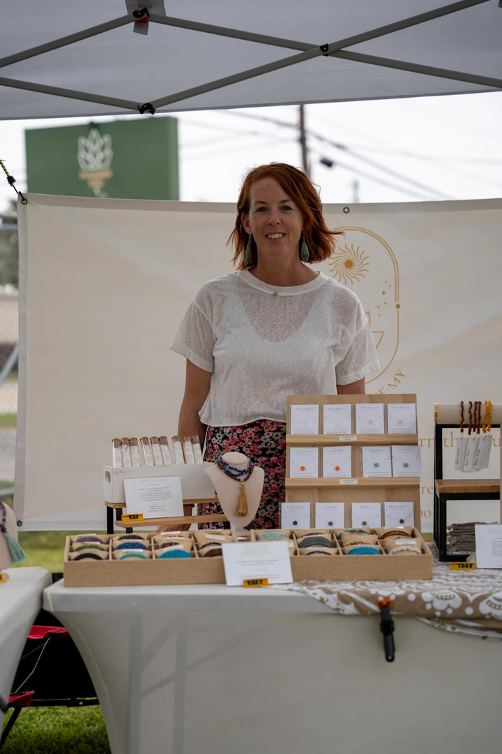 A maker in white standing behind a candle display.