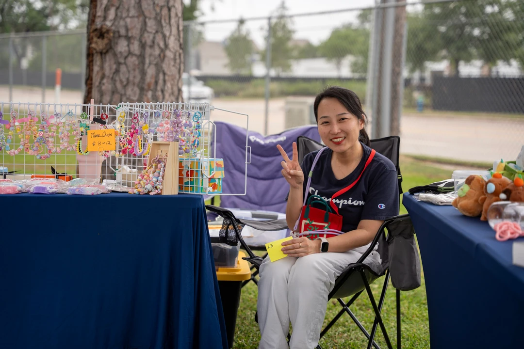 A seated maker beside a rack of colorful accessories.