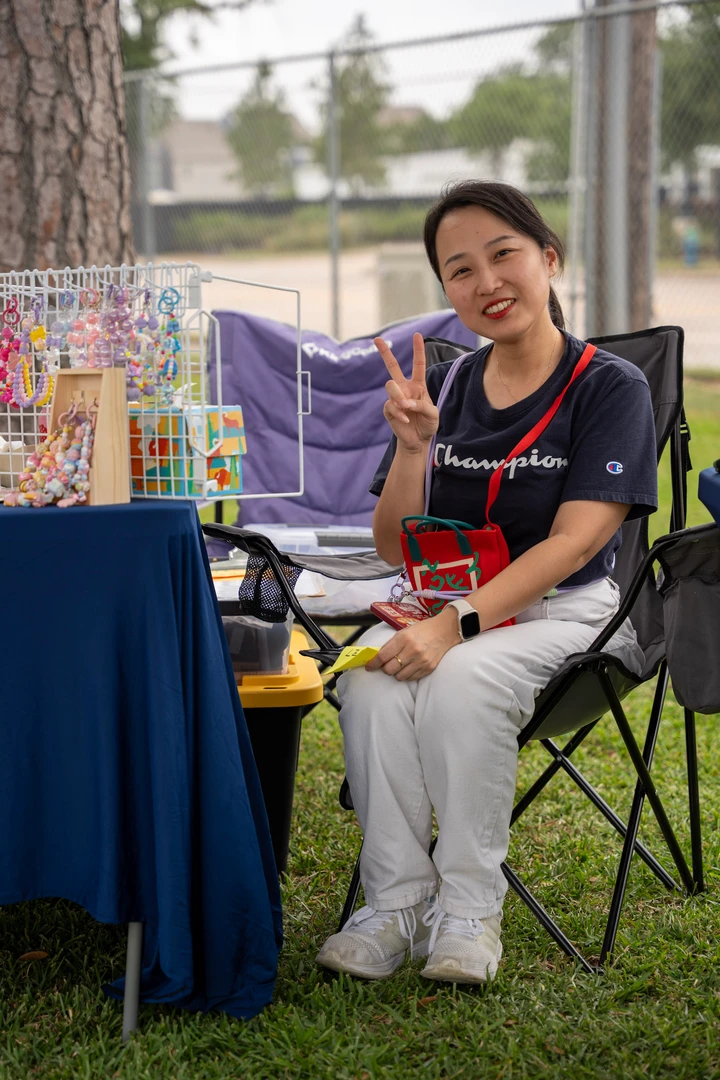 A seated maker beside a rack of colorful accessories.