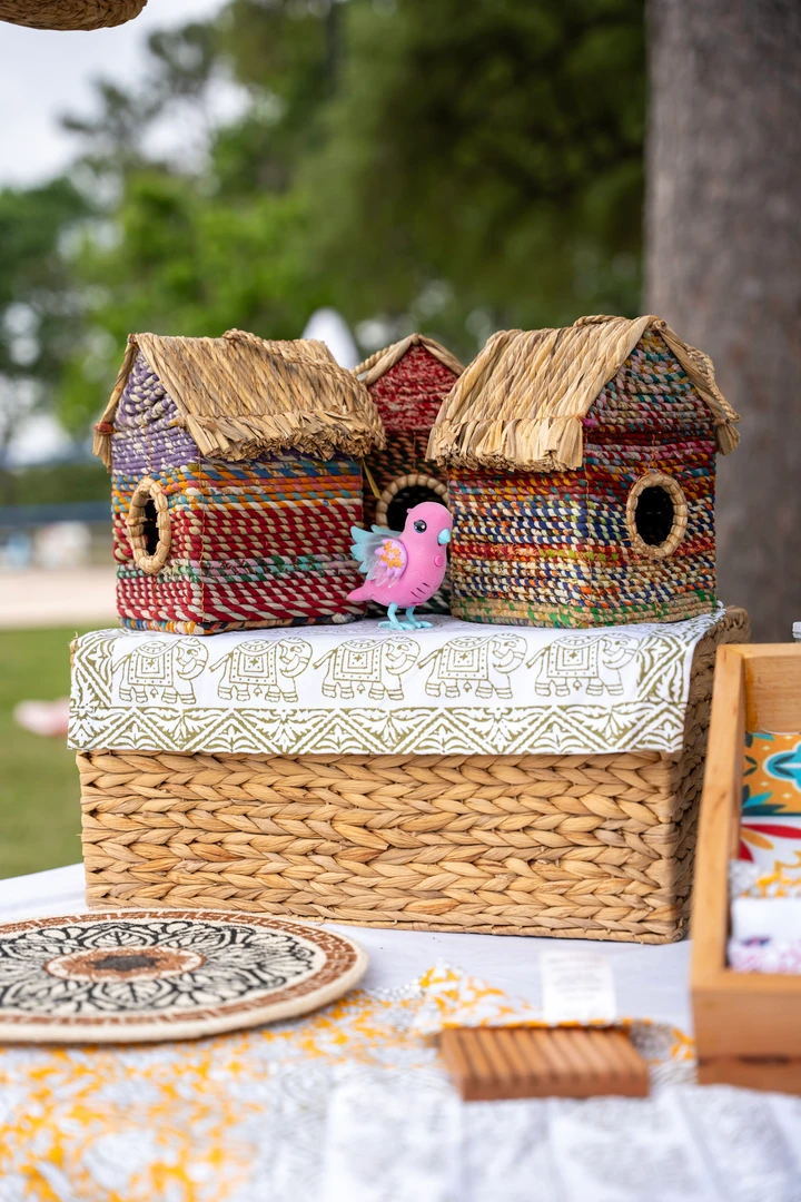 Woven and wooden birdhouses displayed beneath a market canopy.