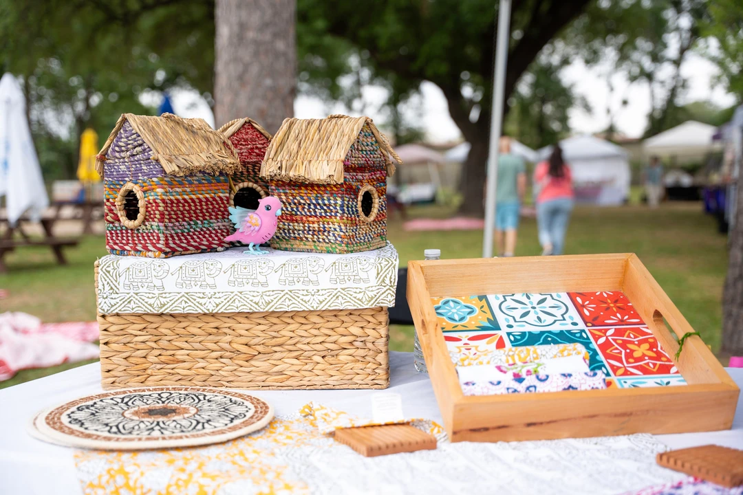 Woven and wooden birdhouses displayed beneath a market canopy.