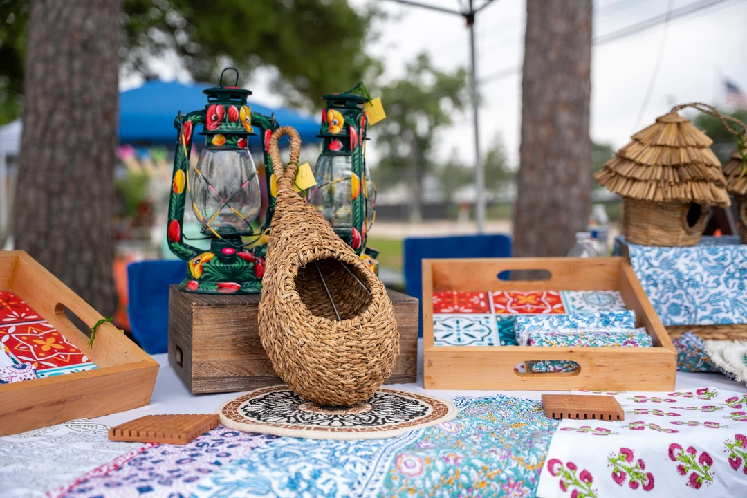 Woven and wooden birdhouses displayed beneath a market canopy.