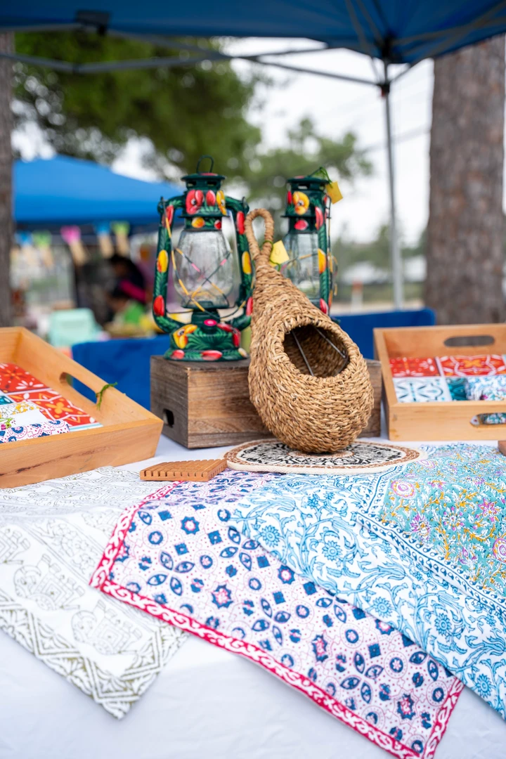 Woven and wooden birdhouses displayed beneath a market canopy.