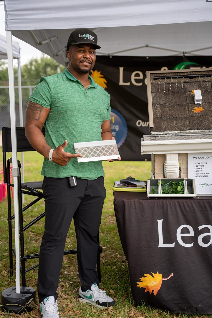 A vendor in green at the LeafFilter demonstration booth.