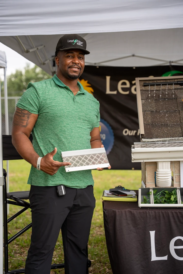 A vendor in green at the LeafFilter demonstration booth.