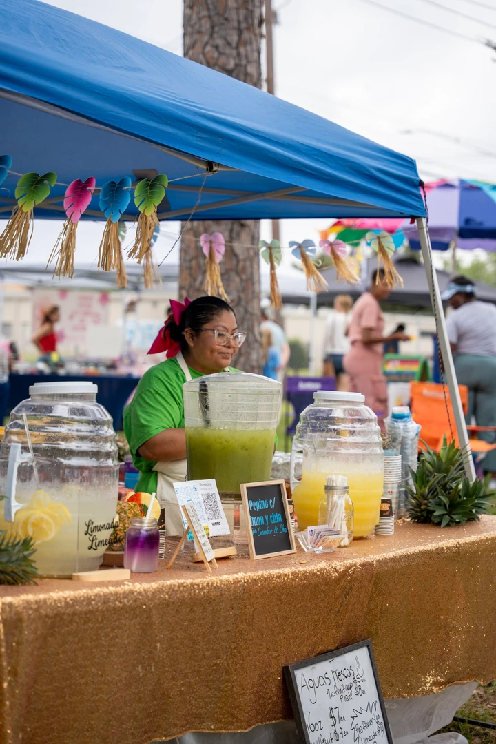 A drink vendor and visitors at an outdoor beverage stall.