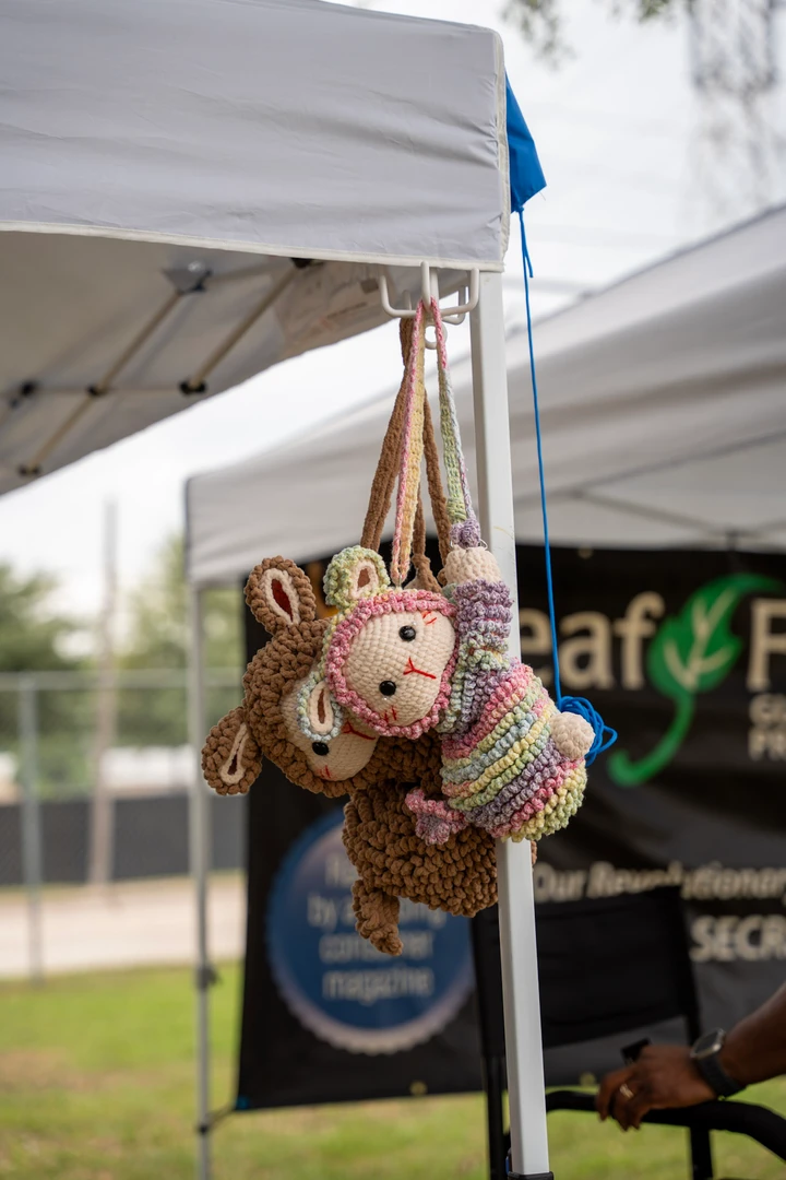 Crocheted animal bags hanging from a market canopy.
