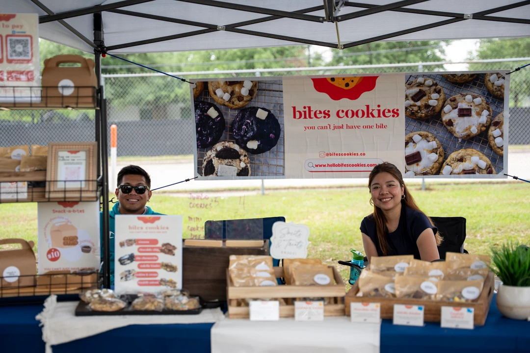Two makers standing behind a baked-goods display.