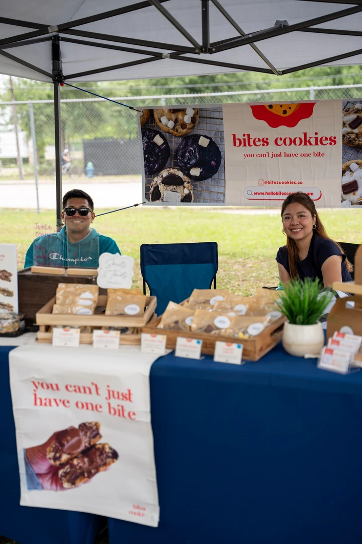 Two makers standing behind a baked-goods display.