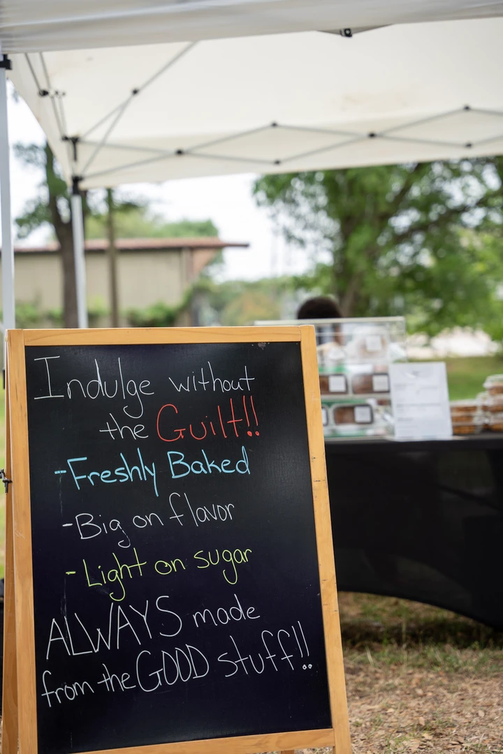 A handwritten baked-goods menu beneath a market canopy.