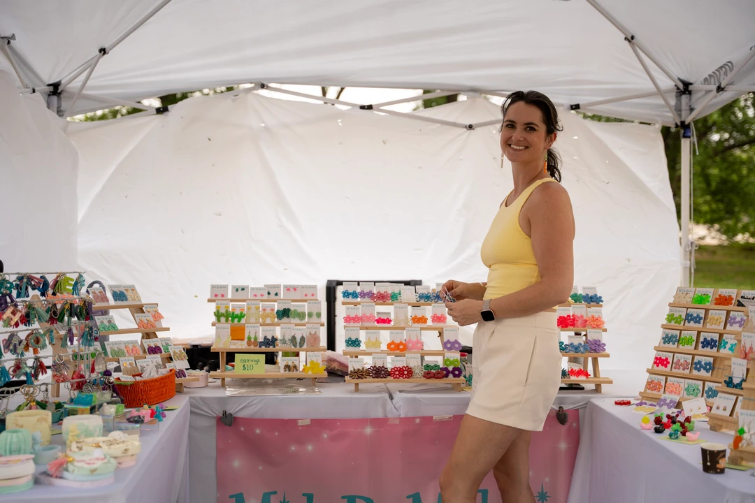 A maker in a yellow top behind her colorful market display.