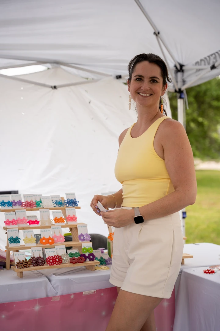 A maker in a yellow top behind her colorful market display.