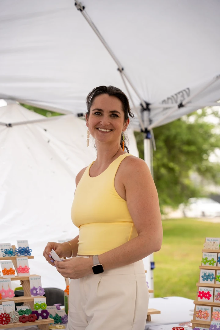 A maker in a yellow top behind her colorful market display.