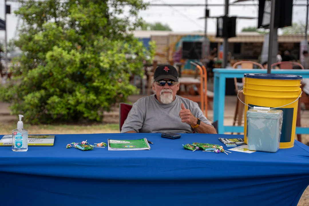 A vendor behind a display table beneath an outdoor canopy.