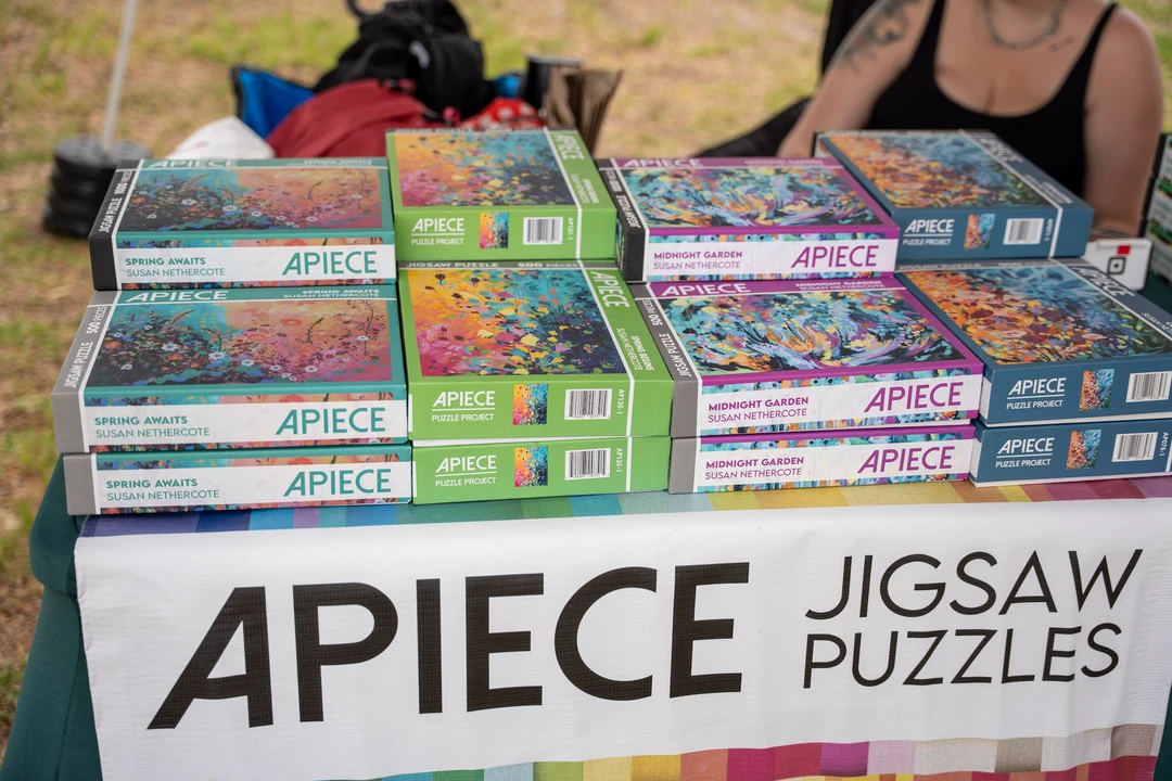 Boxes of Apiece jigsaw puzzles stacked on a market table.