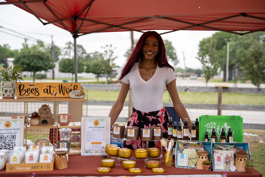 A smiling candle maker in white at the Honey Charm Scents stall.
