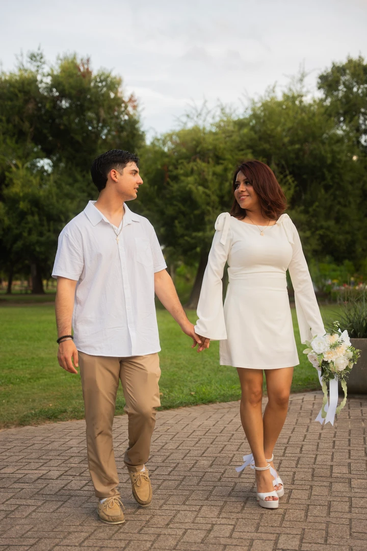 Mag and Michelle walk hand in hand along a tree-lined path.