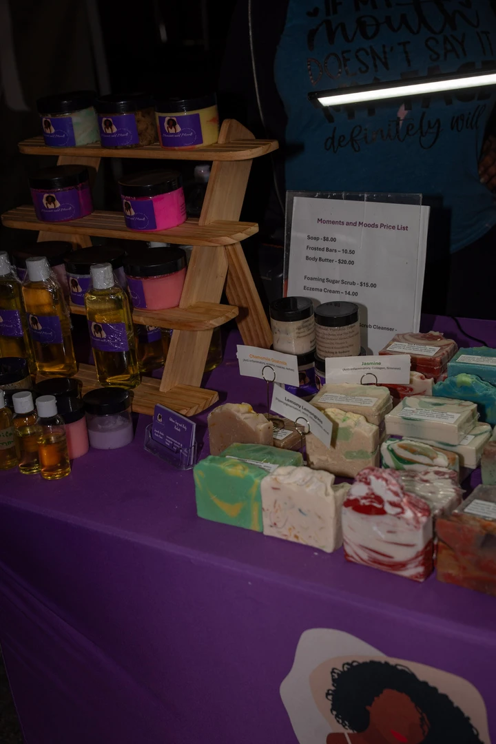 Soap and small gifts arranged on a purple-covered table.