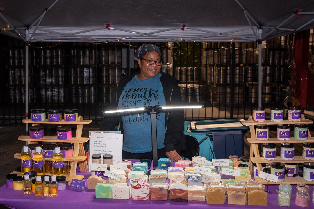A maker behind a brightly lit soap and gift display.