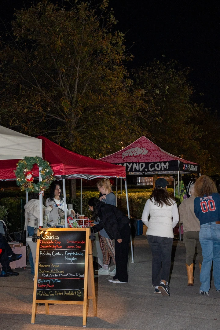 Shoppers walking between outdoor market tents after dark.