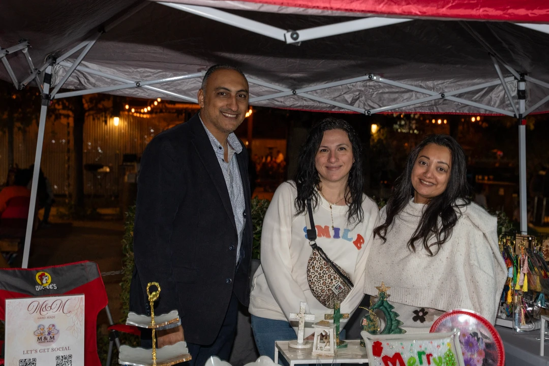 Three smiling makers behind a holiday gift display.